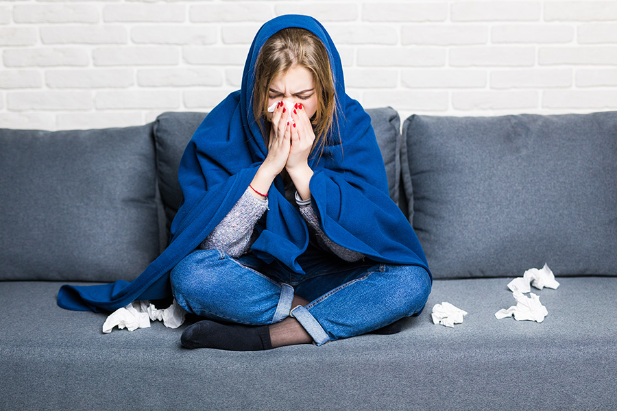 Sick Woman With Rheum And Headache Holding Napkin, Sitting On Sofa With Coveret And Pills At Home