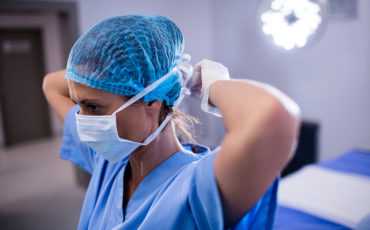 Female Nurse Tying Surgical Mask In Operation Theater