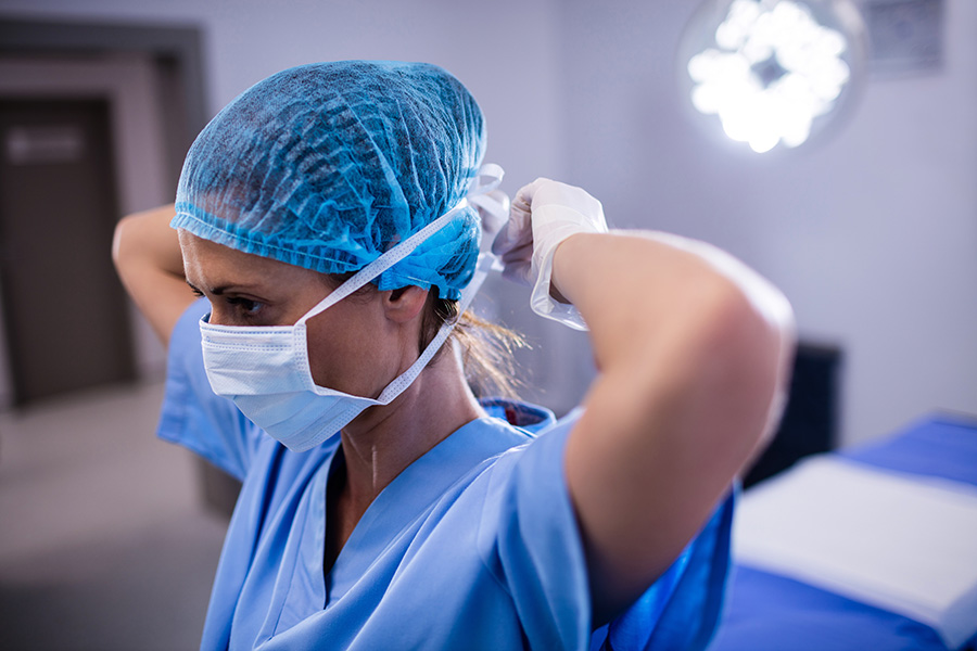 Female Nurse Tying Surgical Mask In Operation Theater