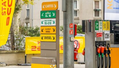 station service avec au premier plan la liste des carburants et une pompe