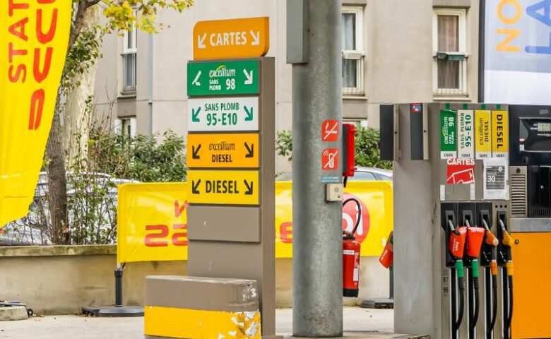 station service avec au premier plan la liste des carburants et une pompe